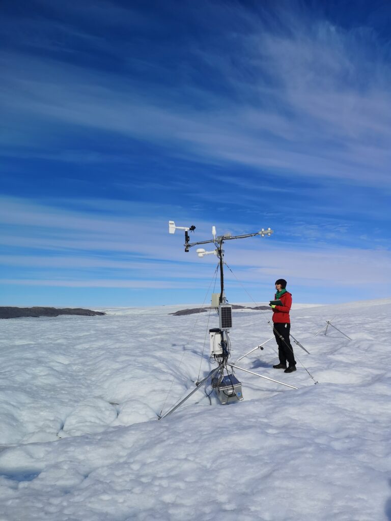 On the ice sheet. Weather station with person wearing red.