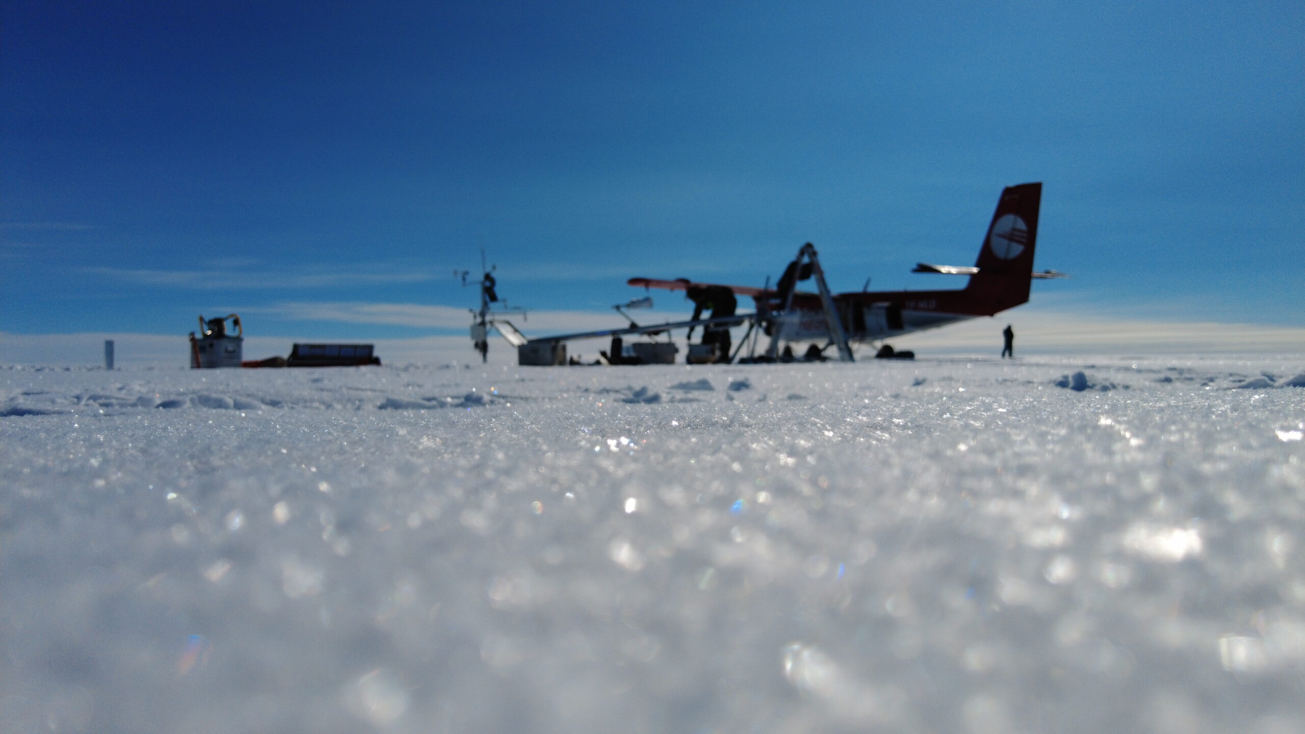 On the ice sheet. Snow crystals with blurry airplane in the background.