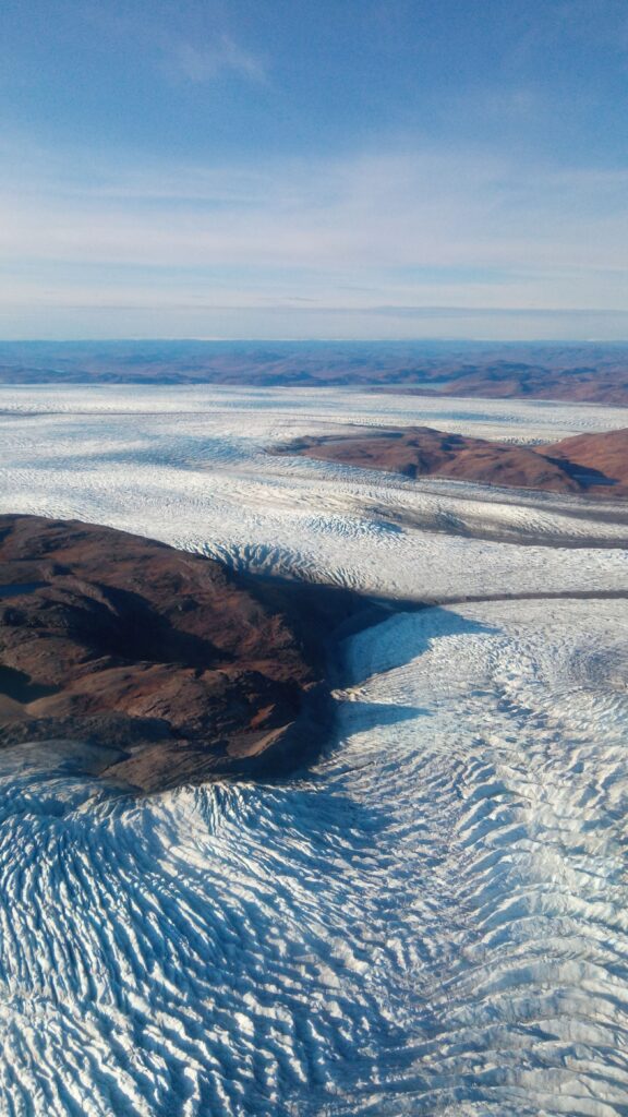 Ice flowing around rocky outcrops. View from helicopter.