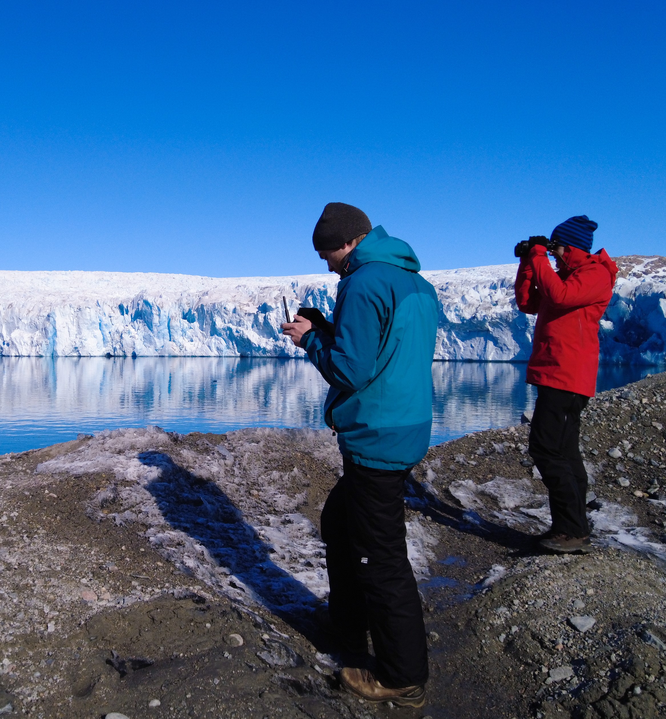 Scientists in front of a glacier keeping an eye on the UAV.